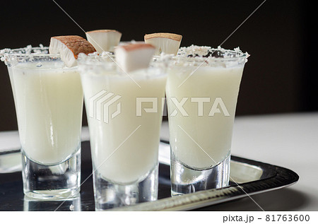Coconut cocktail in drink shot glass based on the rum decorated with coconut flakes served on a silver tray 81763600