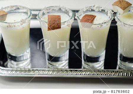 Coconut cocktail in drink shot glass based on the rum decorated with coconut flakes served on a silver tray 81763602