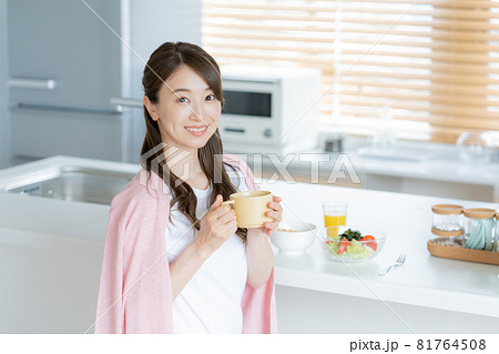 ダイニングキッチンで朝食を食べながら振り向く若い女性 81764508