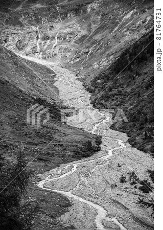 Narrow twisted rocky stream in alpine valley. Gschlosstal Valley, Hohe Tauern National Park, East Tyrol, Austrian Alps. Black and white image. 81764731