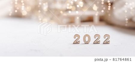 Christmas banner background or greeting card with 2022 wooden text and copy space. Glowing snow bokeh. Winter holidays on white background 81764861