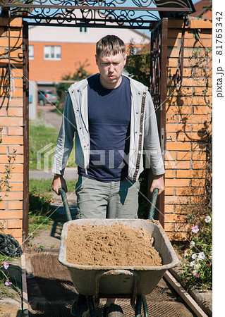 A man unloads sand into a cement mixture for pouring a garden path 81765342