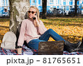 Young woman working with laptop outdoors and holding phone 81765651