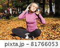 A young woman plays sports outside in an autumn park and listens to music with headphones 81766053