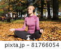 A young woman plays sports outside in an autumn park and listens to music with headphones 81766054