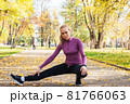 Young woman does stretching exercises in the park. Sports outside in autumn 81766063