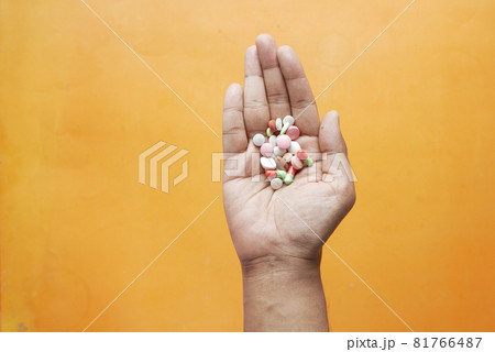 man's hand with medicine and capsule on orange background  81766487
