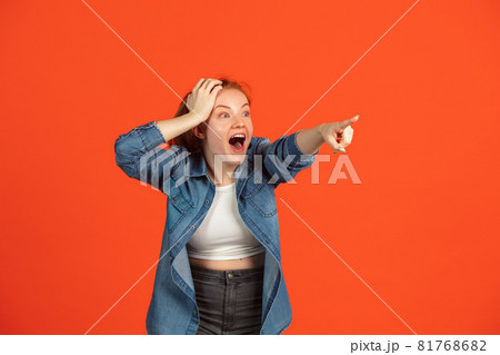 Cropped image of young girl in casual clothes pointing somewhere isolated over red background Cropped image of young girl in casual clothes pointing somewhere isolated over red background 81768682