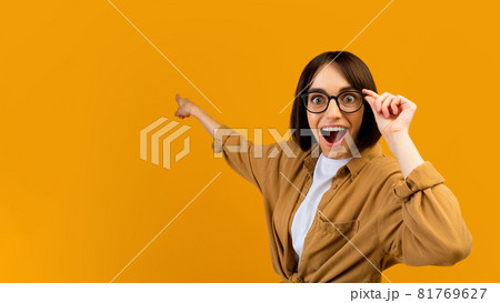 Seasonal sale. Surprised lady pointing at empty space over yellow studio background, banner design, panorama Seasonal sale. Surprised lady pointing at empty space over yellow studio background, banner design, panorama 81769627