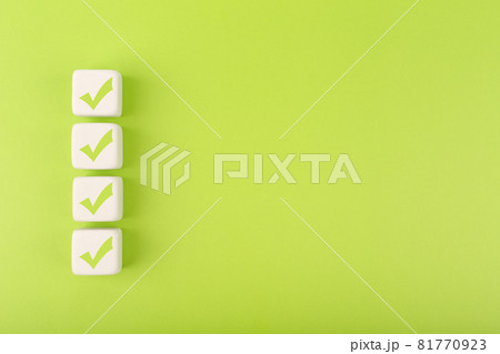Four checkmarks on white cubes against bright green background with copy space 81770923