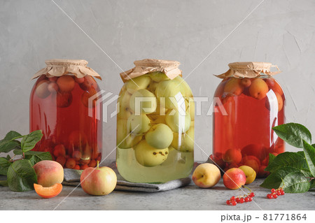 Three canned apple and cherry compote in large glass jars on gray table. Three canned apple and cherry compote in large glass jars on gray table. 81771864