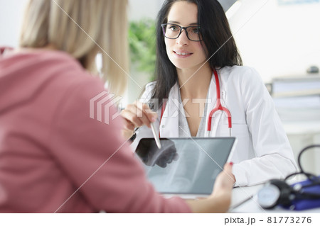 Doctor shows woman patient an X-ray of lungs on tablet closeup 81773276
