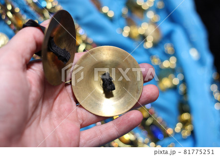 Bellydancer hand close up with finger cymbal with dance costume in background 81775251