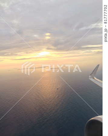 夕陽を背景に大空を羽ばたく飛行機の上空画像 81777702