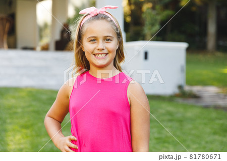 Portrait of smiling caucasian girl outside house looking at camera in garden 81780671