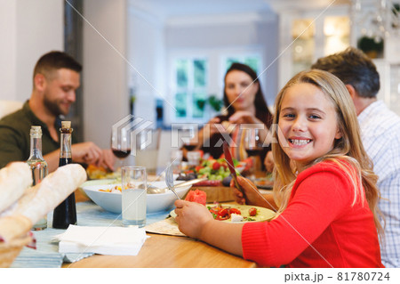 Portrait of caucasian grandfather and parents with daughter sitting at table having dinner Portrait of caucasian grandfather and parents with daughter sitting at table having dinner 81780724
