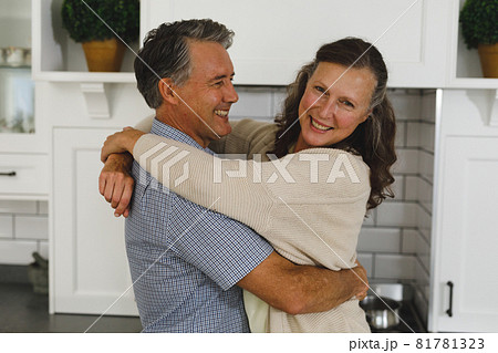 Happy senior caucasian couple in modern kitchen, embracing and smiling 81781323
