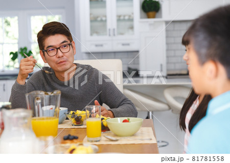 Asian father with son and daughter sitting at table having conversation at breakfast 81781558