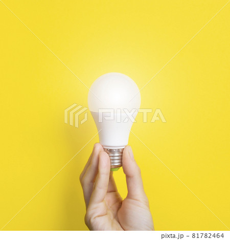 Hand holding a LED light bulb on bright yellow background. Using economical and environmentally friendly light bulb concept. Idea concept. Energy saving lamp in woman's hand 81782464