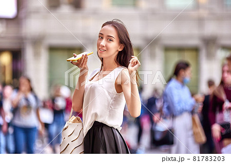 18 year woman speaks on phone on crowded city street. 81783203