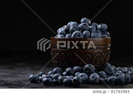 Fresh juicy blueberries in the bowl on the black background. Low key photography Fresh juicy blueberries in the bowl on the black background. Low key photography 81783983