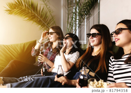 Group of people are watching a movie. Friend girls eat popcorn and drink soda 81794358