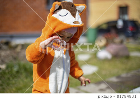 adorable little toddler playing with water in the backyard. child in a fox costume. 81794931