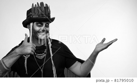 Sinister man with horrible Halloween skeleton makeup ooking at camera, pointing to the left Sinister man with horrible Halloween skeleton makeup ooking at camera, pointing to the left 81795010