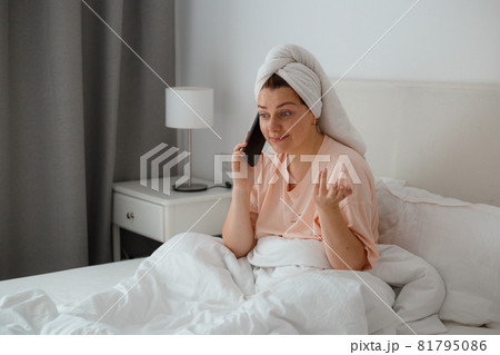 Happy young caucasian woman relax on comfortable bed at home and use cellphone, talk with boyfriend. Concept of gossip Happy young caucasian woman relax on comfortable bed at home and use cellphone, talk with boyfriend. Concept of gossip 81795086