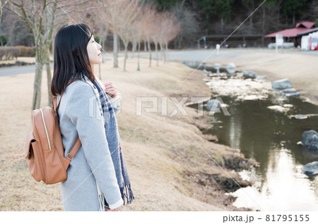冬の公園のせせらぎにたたずむ女性 81795155