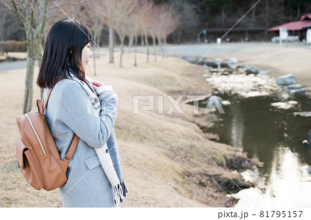 冬の公園のせせらぎにたたずむ女性 81795157