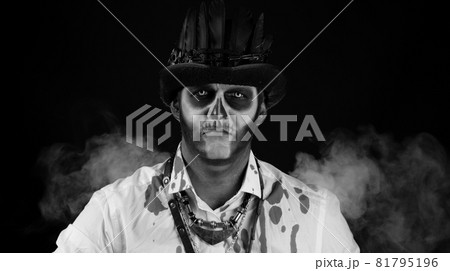 Sinister man with Halloween skeleton makeup in shirt with blood looking at camera, trying to scare 81795196
