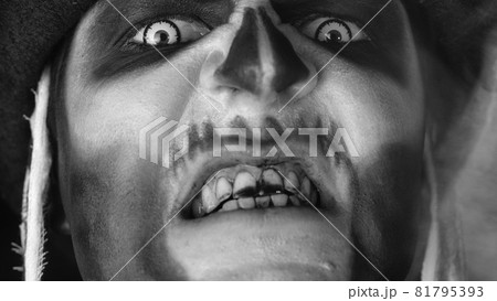 Man with skeleton creepy makeup trying to scare, opening his mouth and showing dirty black teeth 81795393