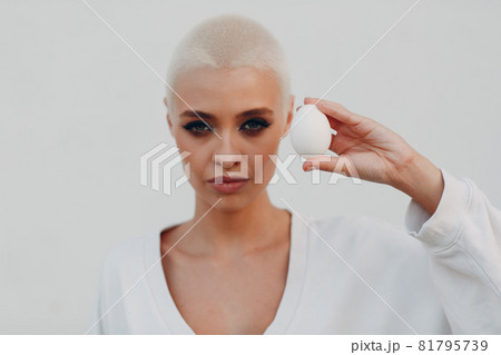 Millenial young woman blonde short hair outdoor smiling portrait with egg. 81795739