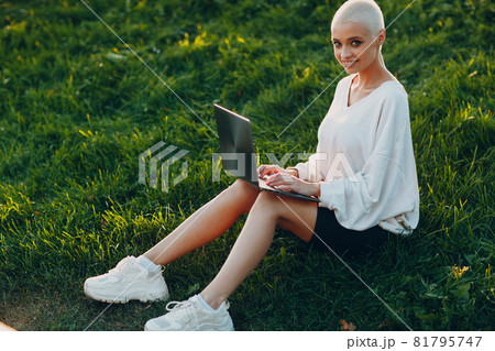 Millenial young woman blonde short hair outdoor smiling portrait with laptop. 81795747