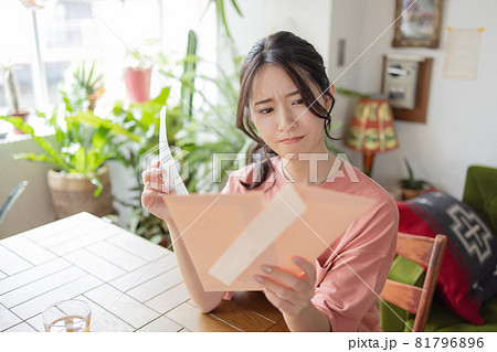 封筒を見て悩む若い女性 81796896