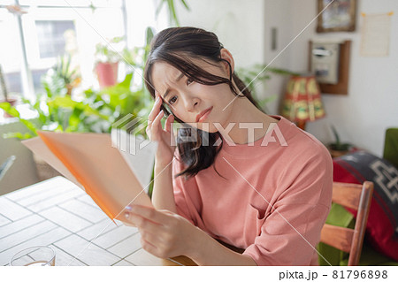 封筒を見て悩む若い女性 81796898