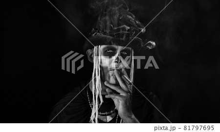 Sinister man with horrible Halloween skeleton makeup smoking cigar, making faces Sinister man with horrible Halloween skeleton makeup smoking cigar, making faces 81797695
