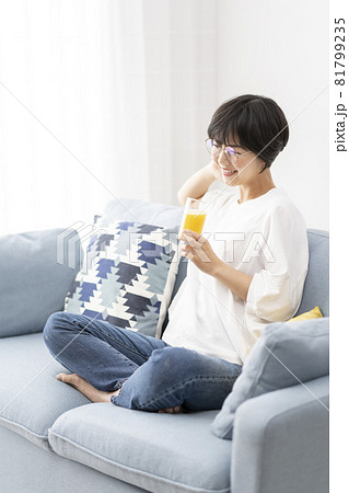 ソファーでオレンジジュースを飲む女性 81799235