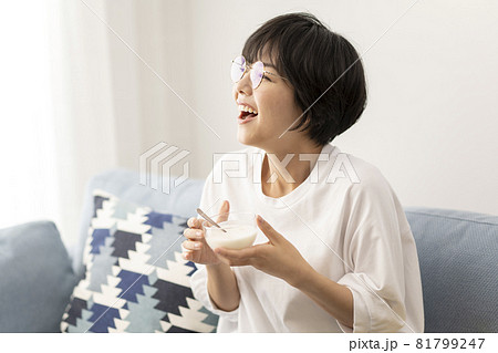 ソファーでヨーグルトを食べる若い女性 81799247