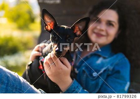 Young woman with her little dog outdoors. 81799326