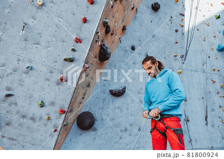 Safety climbing. Young man professional rock climber checking sports equipment before climbing at training center in sunny day, outdoors. Safety climbing. Young man professional rock climber checking sports equipment before climbing at training center in sunny day, outdoors. 81800924