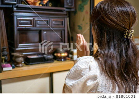 仏間で仏壇に手を合わせる若い女性の後姿 81801001
