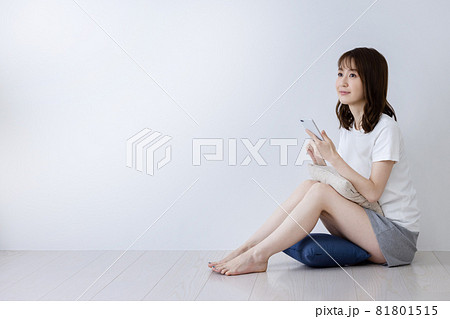 床に座りながらスマートフォンを使う女性の写真素材