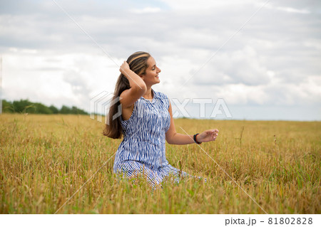 beautiful swarthy young woman sits in a meadow on a sunny day and enjoys the summer weather 81802828