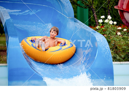 happy an 8 year old boy is riding in the water Park on inflatable circles on water slides with splash happy an 8 year old boy is riding in the water Park on inflatable circles on water slides with splash 81803909