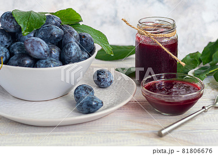 Plum jam in a jar. In the background there are plums. Tkemali sauce. Preparing for winter. Light background. 81806676