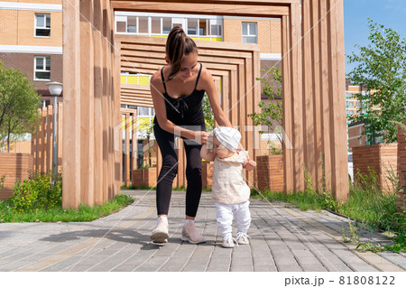 toddler baby girl with mom walk in the city courtyard, child learns to walk toddler baby girl with mom walk in the city courtyard, child learns to walk 81808122