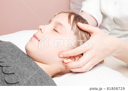 Girl receiving osteopathic treatment of her head Girl receiving osteopathic treatment of her head 81808729