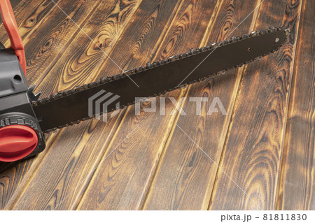 Electric chain saw on wood on a wooden background. Top view Electric chain saw on wood on a wooden background. Top view 81811830